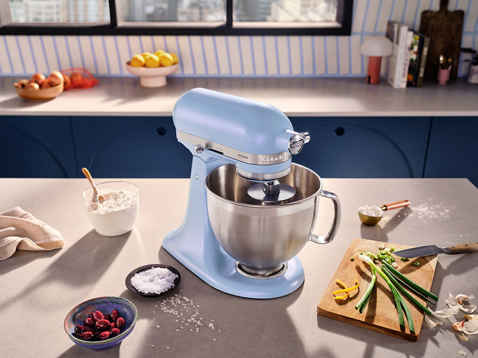 KitchenAid KSM195PSOA Blue Salt tilt-head mixer with its handled stainless-steel bowl in a kitchen setting; the image does not show the separate three-quart bowl or full accessory set.